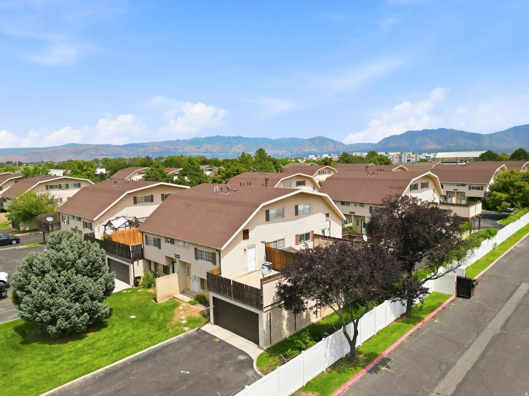 Established residential neighborhood featuring multiple two-story homes with curved roof lines, composite or asphalt shingle roofing, and attached garages