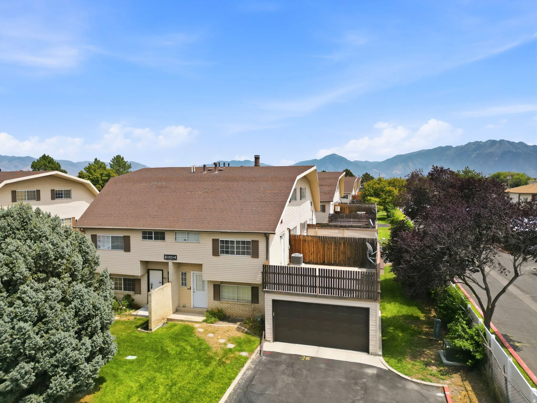 Two-story exterior with a brown shingle roof, attached garage, and a balcony with wood railing