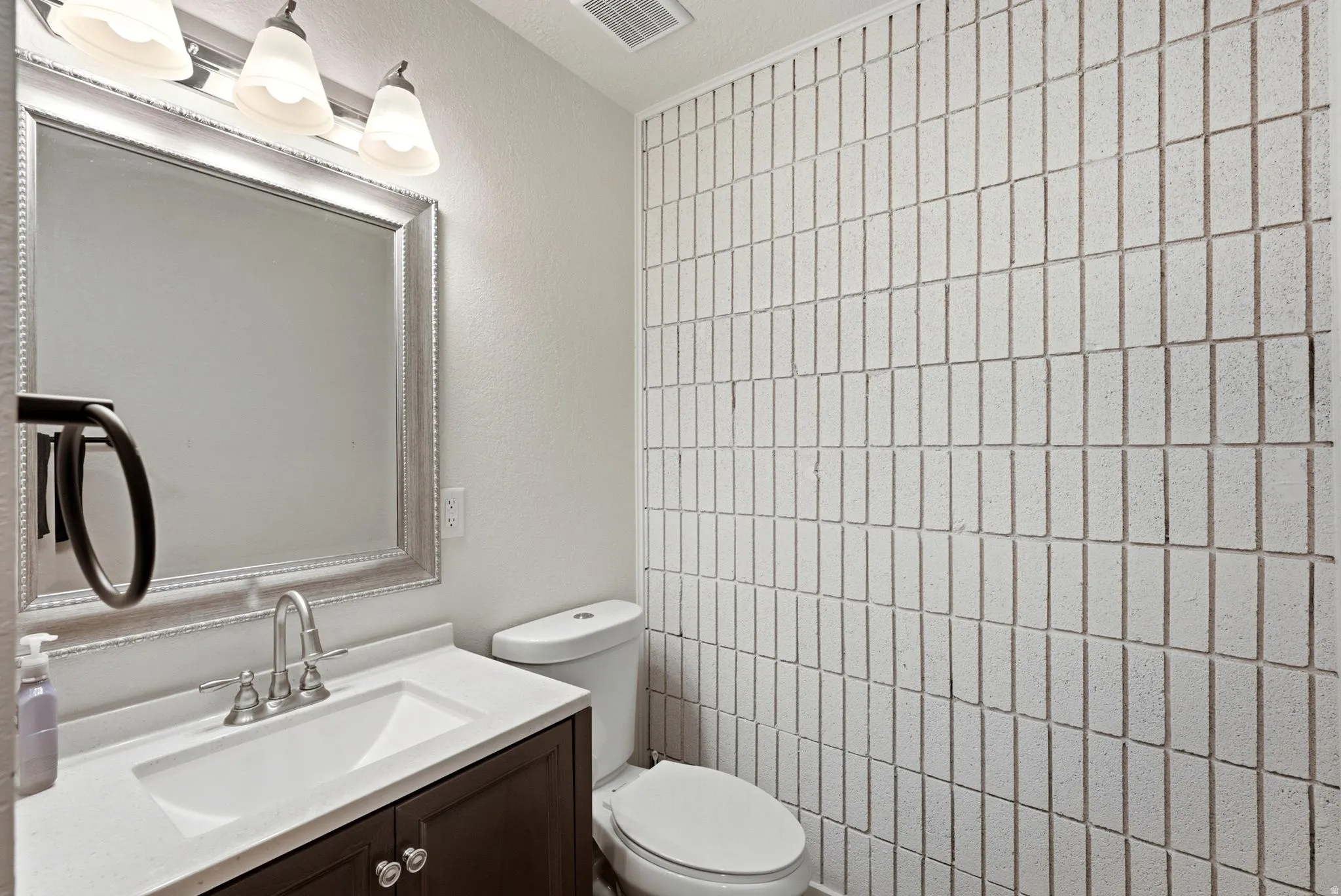 Contemporary bathroom featuring a dark wood-finish vanity with an integrated rectangular sink, polished chrome faucet fixtures, and white quartz countertop