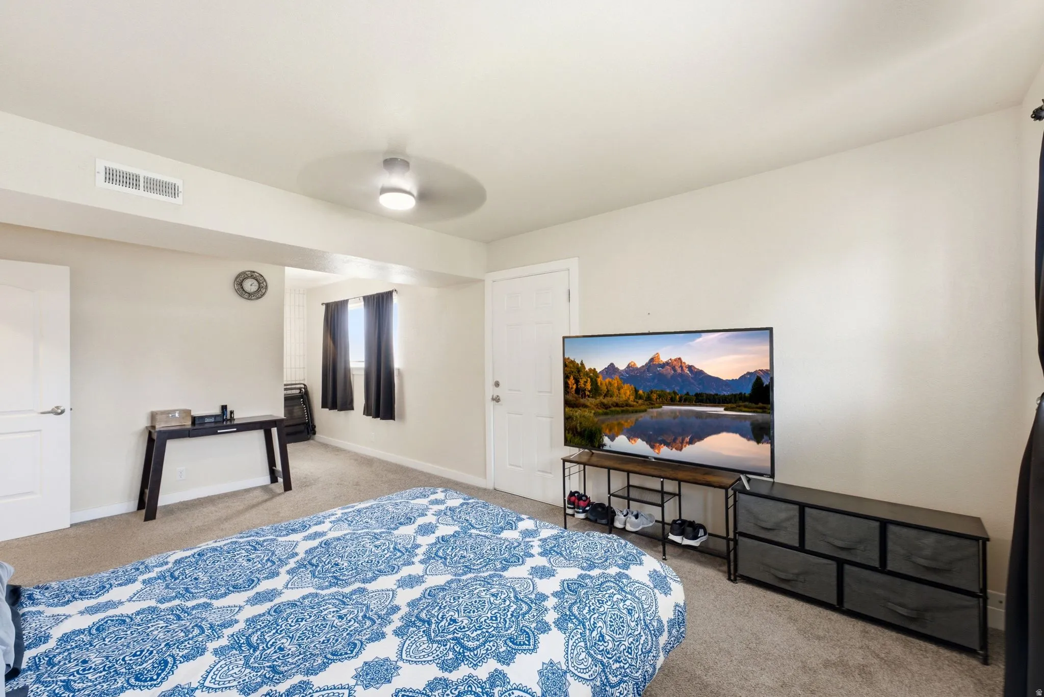 Spacious primary bedroom with carpet flooring, ceiling fan with integrated lighting, and ample natural light from multiple windows