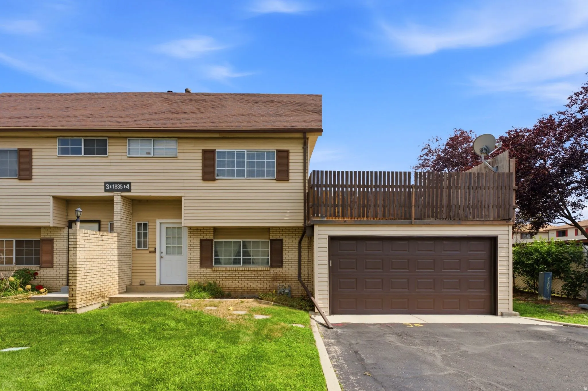 Two-story residence featuring light-colored siding, a brown roof, and an attached garage with a dark brown door