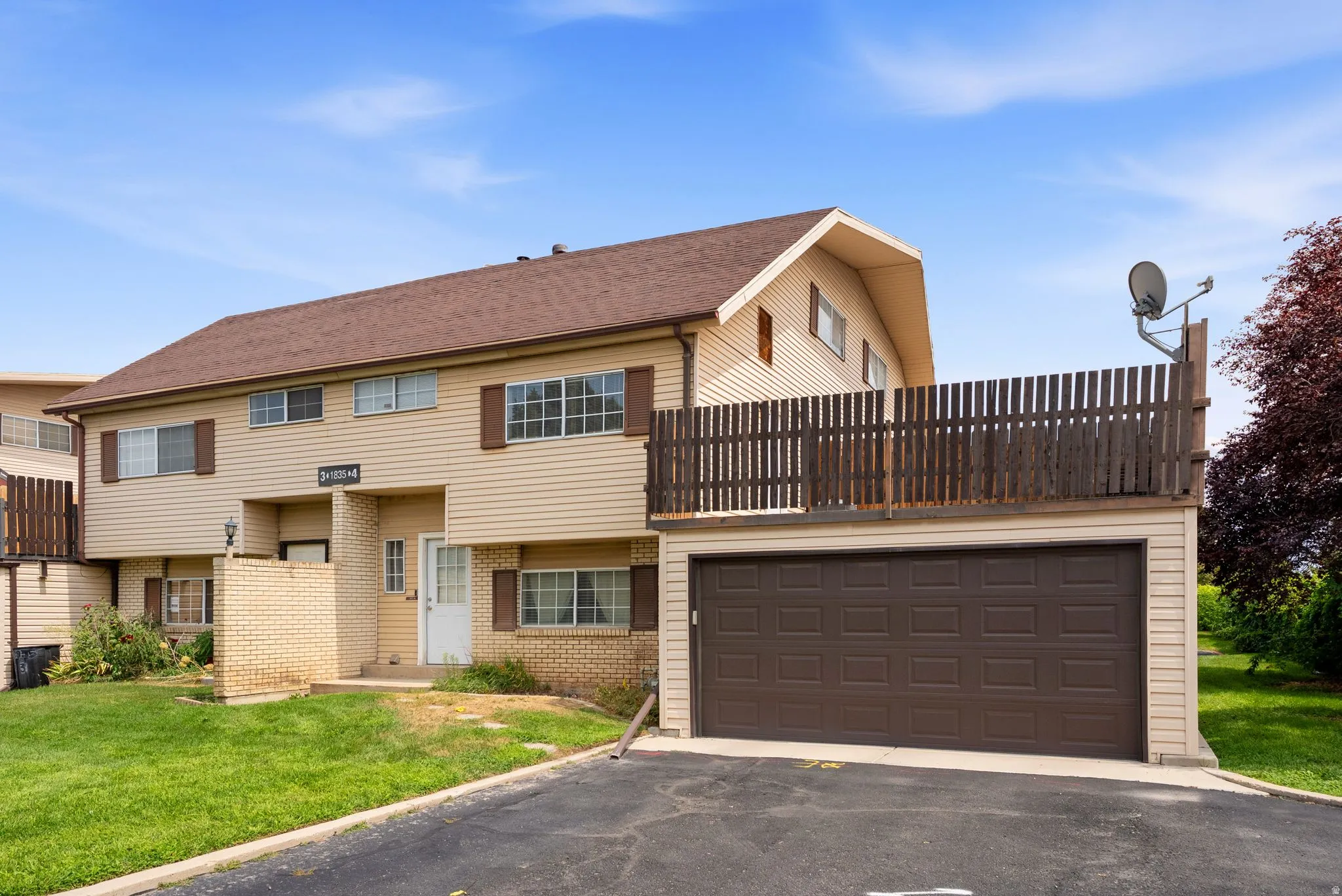 Two-story residential building with light-colored siding, a brown shingle roof, and exterior shutters