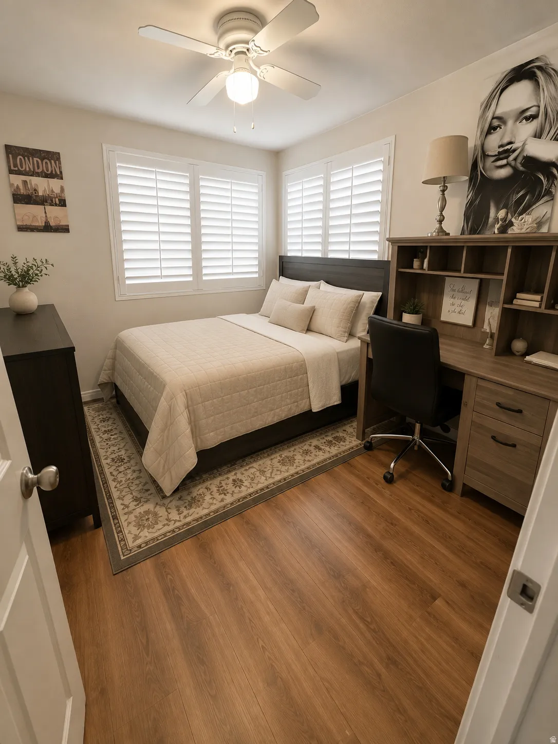 Wood-finish flooring throughout, multiple windows featuring plantation shutters, ceiling fan with integrated lighting, and a built-in desk with shelving