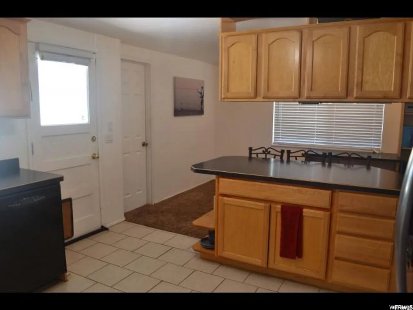 Spacious kitchen featuring wood-finish cabinetry, black countertops, gas cooktop, and stainless steel appliances