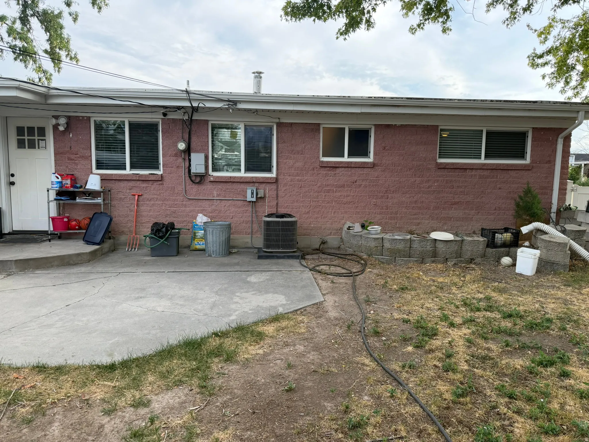 Red brick exterior with multiple windows and a concrete patio