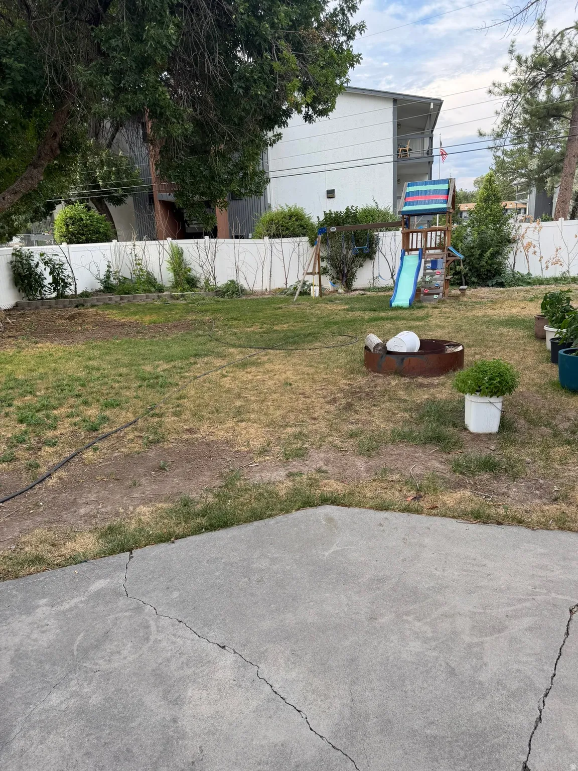 Expansive yard featuring a concrete patio, a privacy fence, and mature trees
