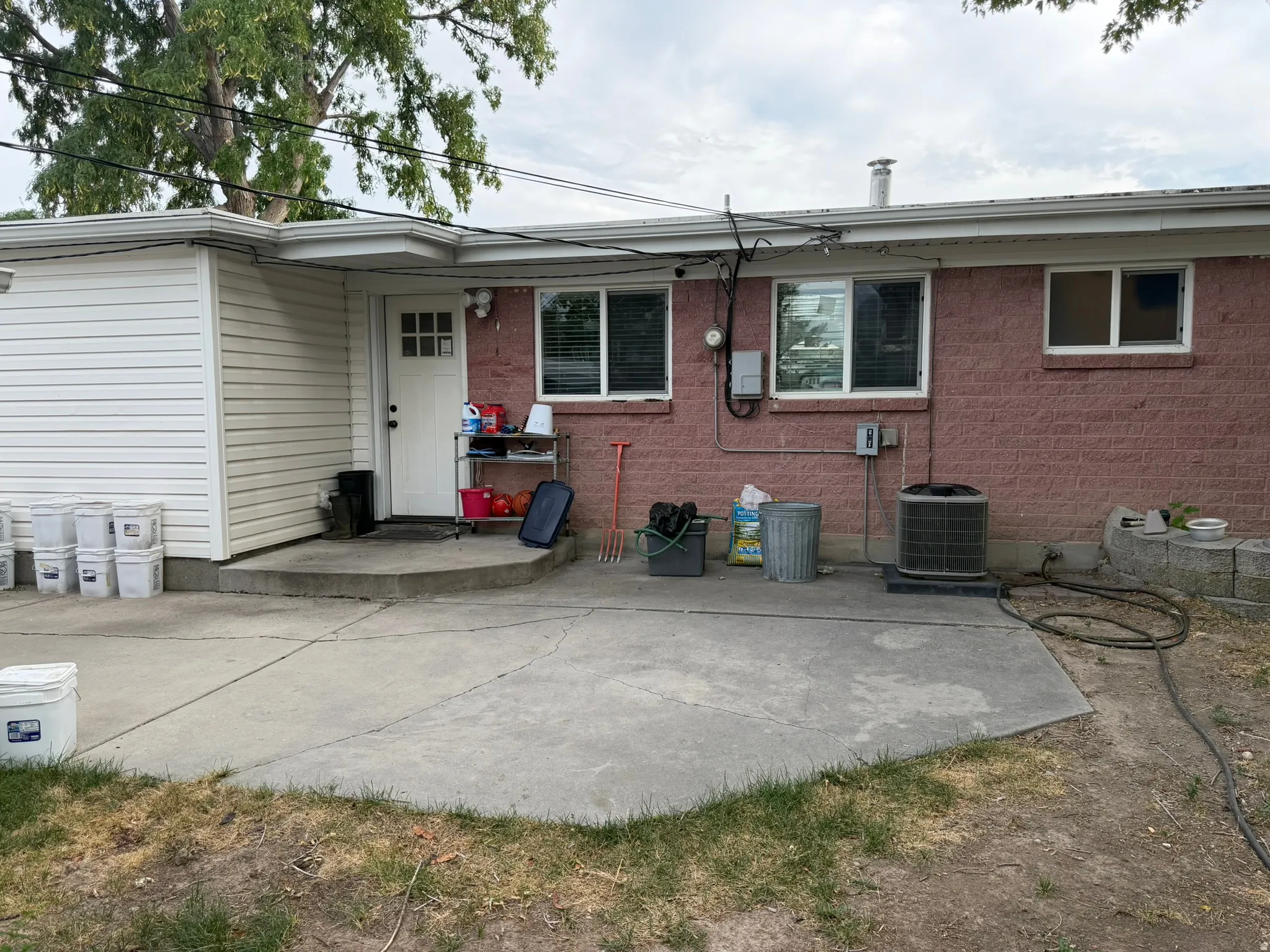 Concrete patio with a brick exterior, white vinyl siding, and white-framed windows