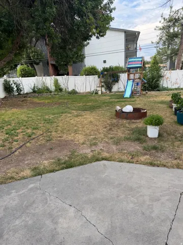 Expansive yard featuring a concrete patio, a privacy fence, and mature trees