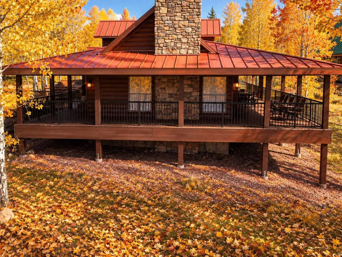 Expansive covered porch with a dark wood railing, stone facade accents, wood siding, and a red metal roof