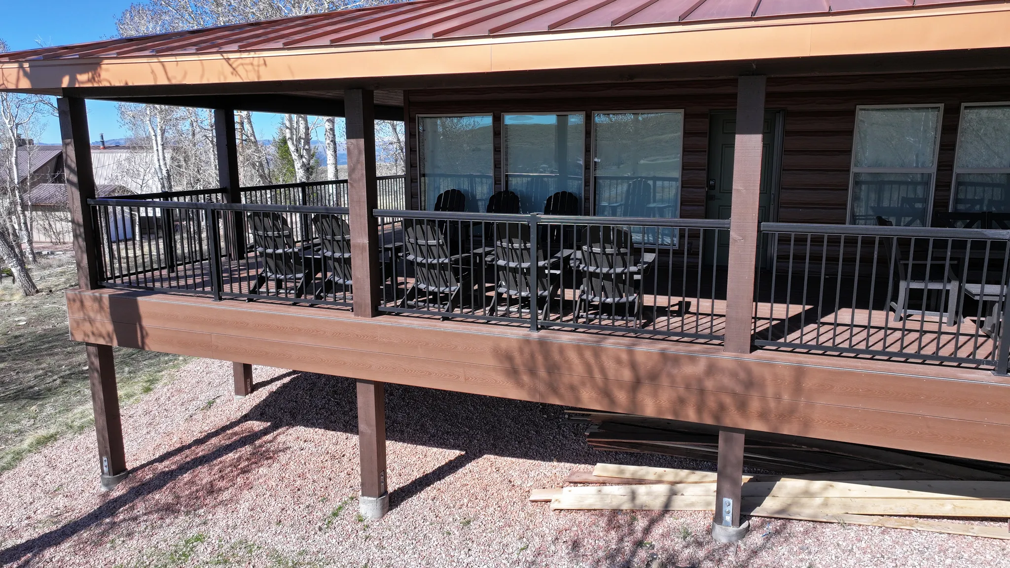 Expansive covered deck with composite decking, black metal railings, and wood support beams
