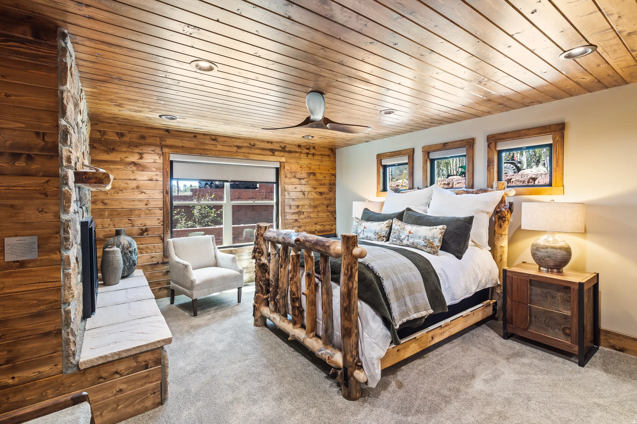 Wood-paneled walls and ceiling, stone fireplace with a stone hearth, recessed lighting, and a ceiling fan