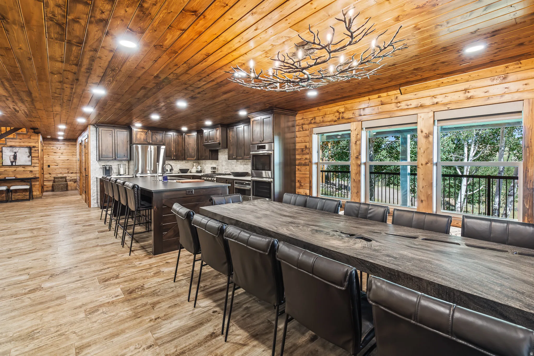 Wood-panel ceilings, wood-finish flooring, and a branch-motif chandelier