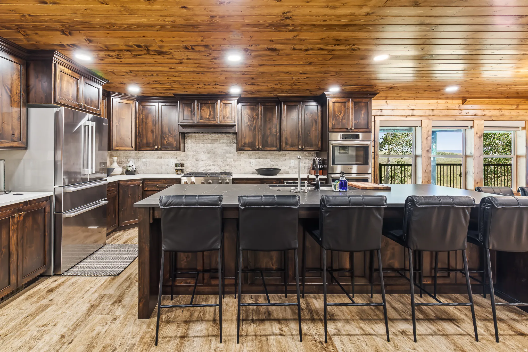 Wood-finish flooring, wood plank ceiling, dark wood cabinetry, stainless steel appliances, and a central island with a countertop
