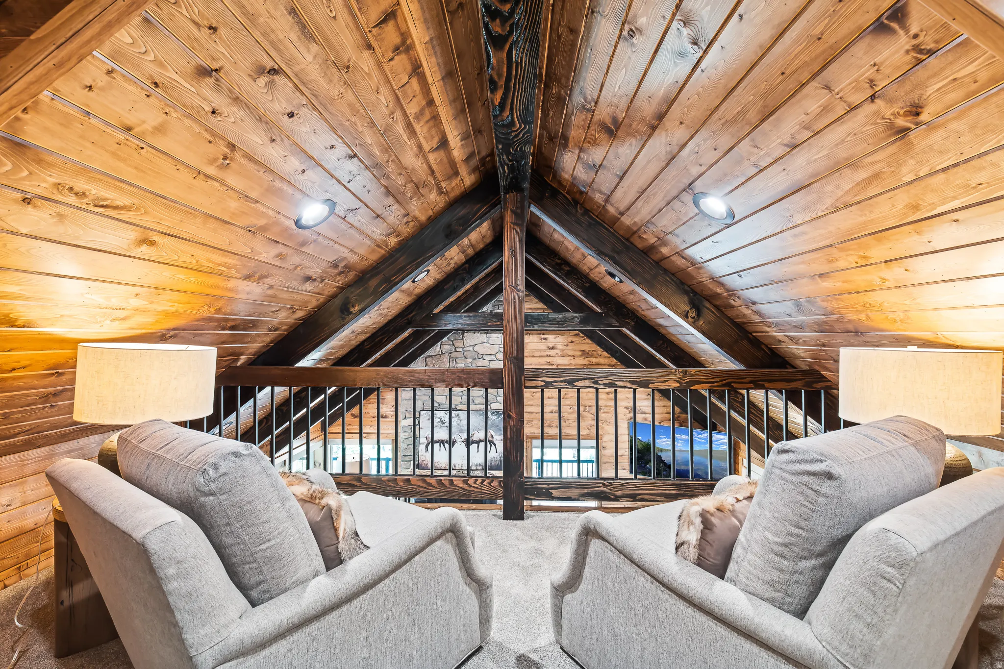 Vaulted wood plank ceilings with exposed beams, recessed lighting, and a wrought iron railing