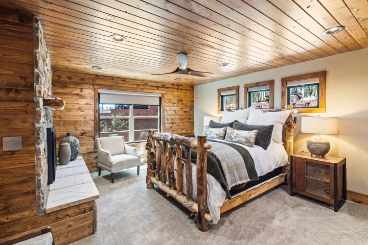 Wood-paneled walls and ceiling, stone fireplace with a stone hearth, recessed lighting, and a ceiling fan