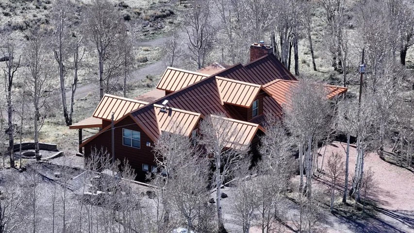 Wood-sided exterior with a multi-pitched metal roof and a stone chimney