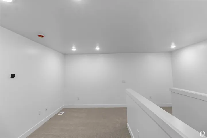 Bright, open room with recessed lighting throughout the ceiling, crisp white drywall finishes, and warm wood-finish flooring