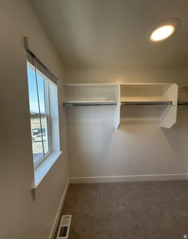 Spacious walk-in closet featuring dual clothing rods, open shelving, and abundant natural light from a large window