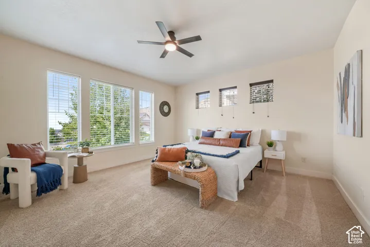 Carpeted room featuring multiple windows with blinds, a ceiling fan with integrated lighting, and neutral wall tones