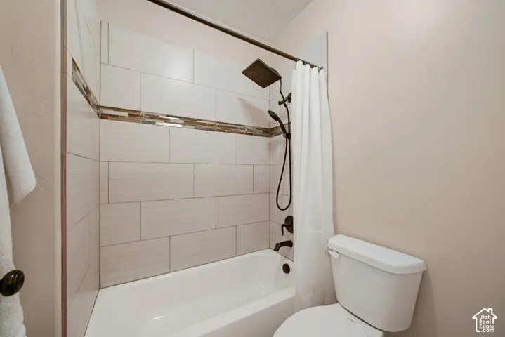 Bathtub with subway tile surround, mosaic accent band, and dark bronze shower fixtures