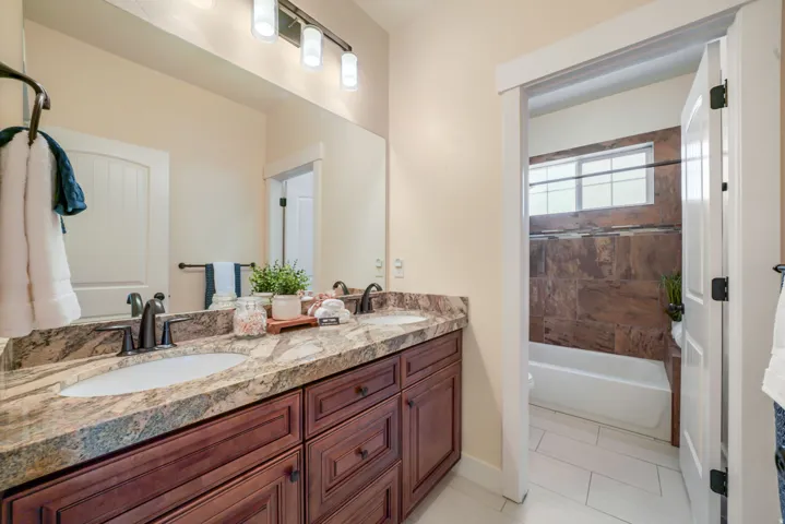 Dual vanity with undermount sinks, stone-look countertop, dark wood-finish cabinetry, and oil-rubbed bronze fixtures