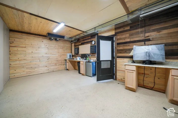 Wood plank wall finishes, wood plank ceiling, light-colored flooring, built-in cabinetry, and integrated countertops