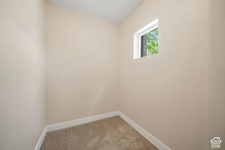 Compact room featuring neutral-toned walls, a single window, and carpet flooring