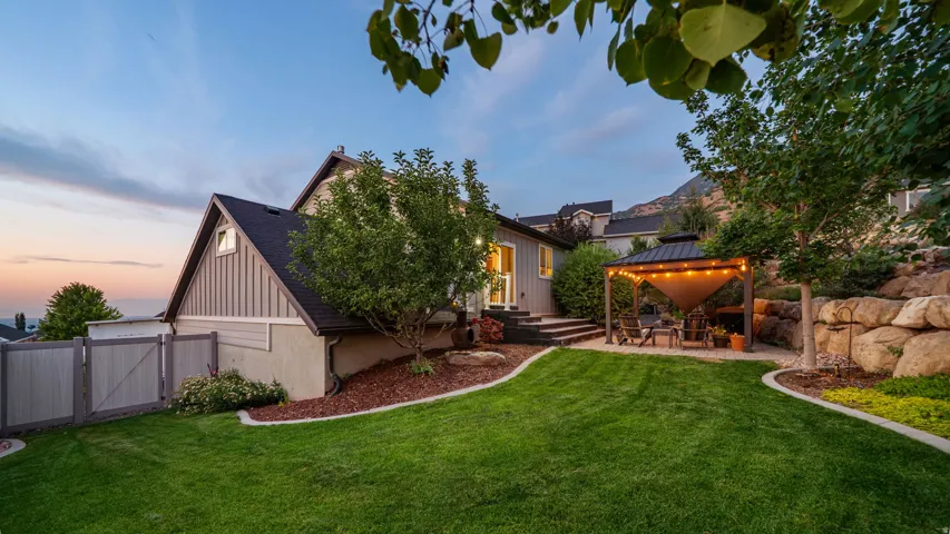 Expansive backyard with a manicured lawn, tiered landscaping, and a fenced perimeter