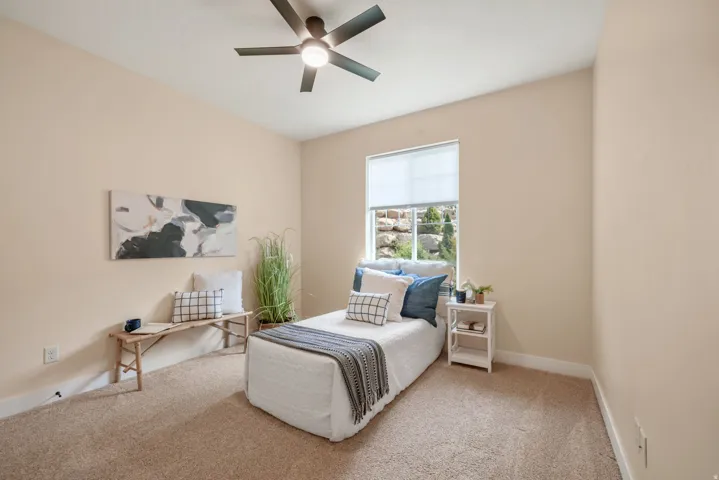 Neutral tone walls, plush carpet flooring, recessed window, and a ceiling fan with integrated lighting