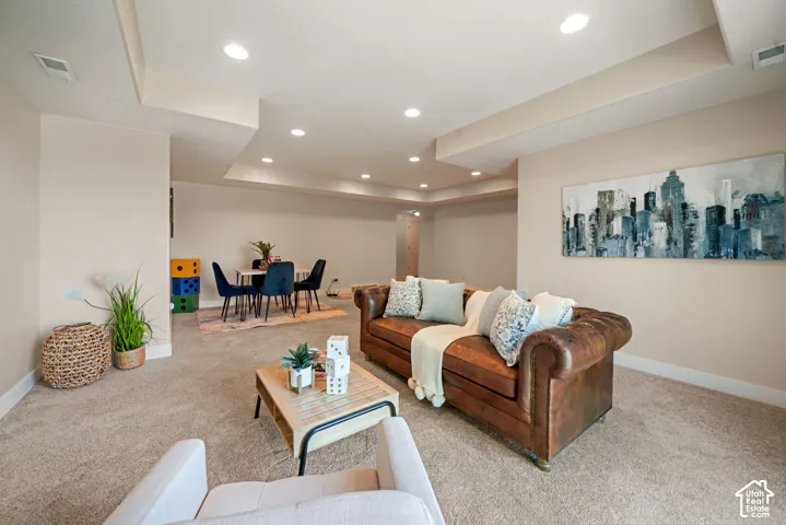 Recessed lighting illuminates the carpeted living area with light beige walls