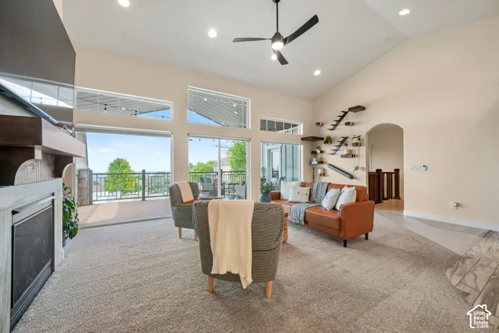 Soaring vaulted ceiling with recessed lighting, large glass sliding doors, built-in fireplace, contemporary ceiling fan, and arched doorway