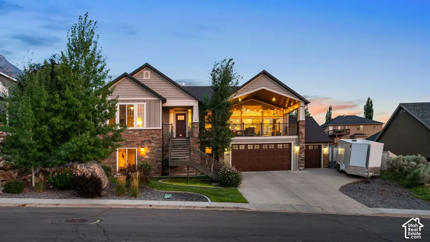 Contemporary exterior featuring stone and siding finishes, an integrated covered deck, a two-car garage with wood-finish doors, a single-car garage, and a concrete driveway