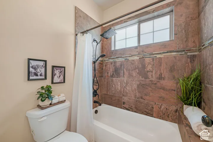 Built-in bathtub with a dark-tiled surround, mosaic tile accent band, and a window with privacy glass