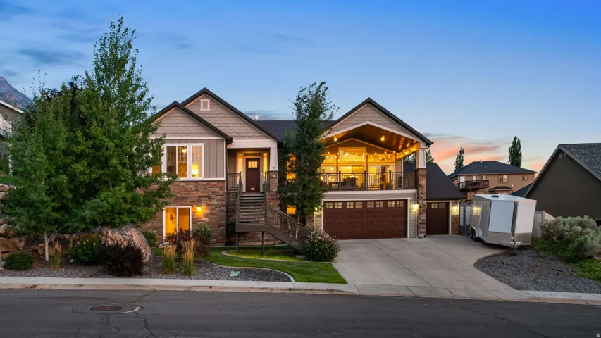 Contemporary exterior featuring stone and siding finishes, an integrated covered deck, a two-car garage with wood-finish doors, a single-car garage, and a concrete driveway