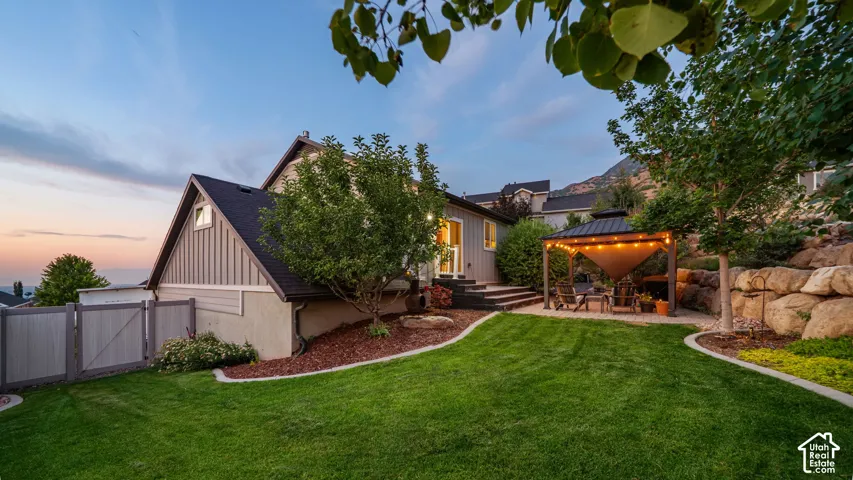 Expansive backyard with a manicured lawn, tiered landscaping, and a fenced perimeter
