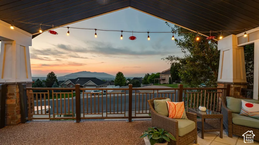 Covered outdoor patio featuring string lighting, stone column accents, and decorative railing