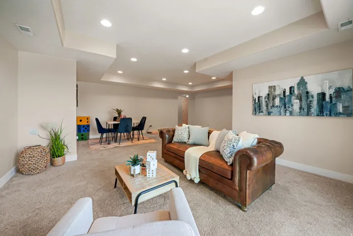 Recessed lighting illuminates the carpeted living area with light beige walls