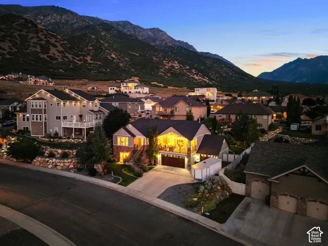 Sloped lot residence featuring a two-car garage, stone and siding exterior, and tiered landscaping