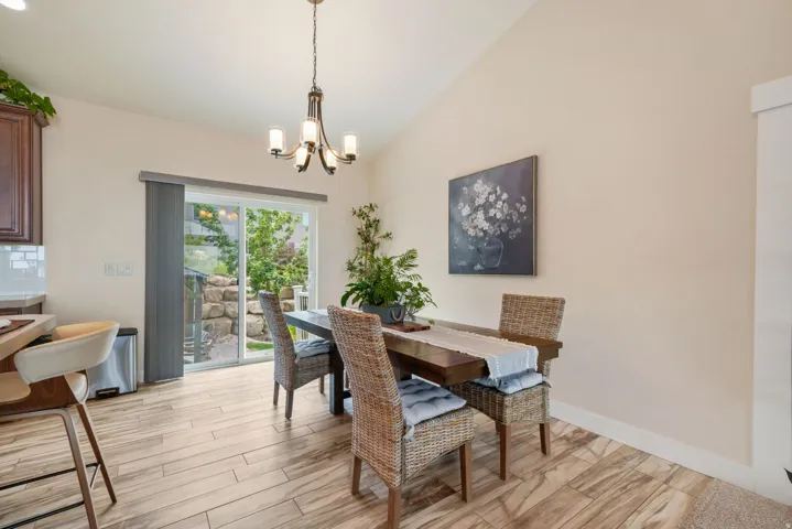 Vaulted ceiling with a chandelier, wood-finish flooring, sliding glass door, and built-in cabinetry