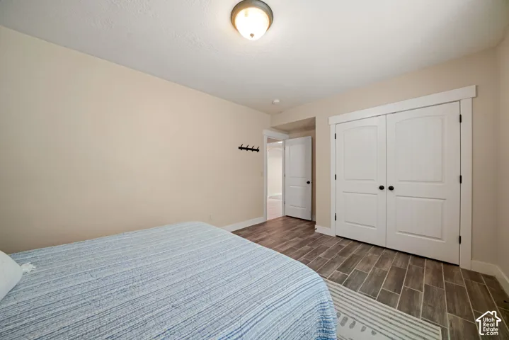 Wood-finish flooring throughout, featuring a double-door closet with arched paneling and dark hardware