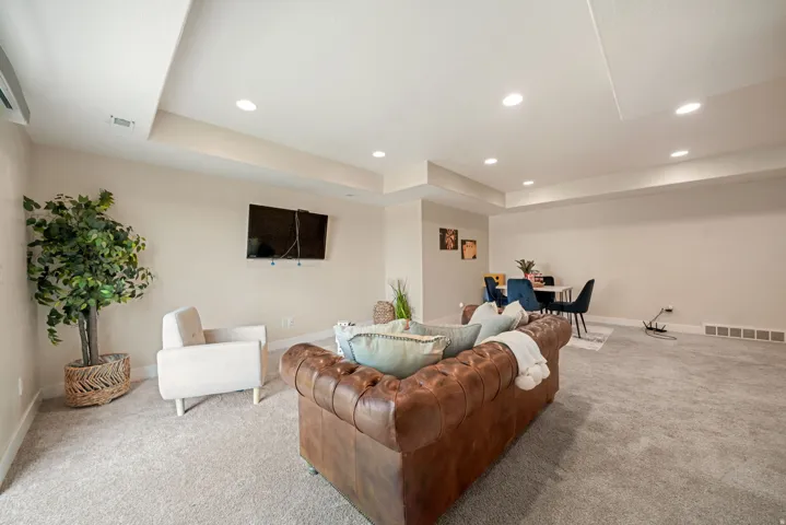 Recessed lighting illuminates the carpeted floor and neutral-toned walls