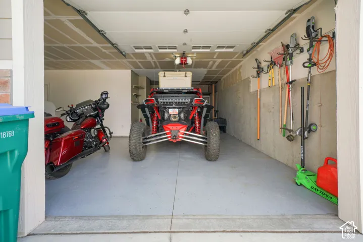 Garage space with a finished concrete floor, exposed ceiling joists, and a wall-mounted storage system