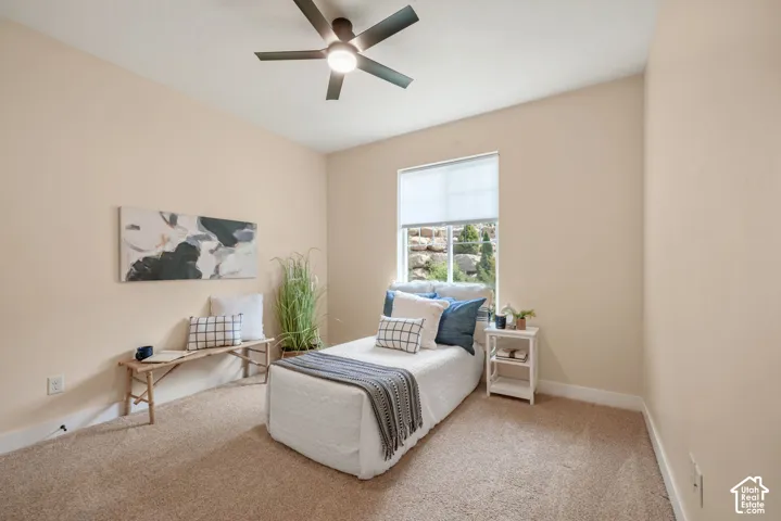 Neutral tone walls, plush carpet flooring, recessed window, and a ceiling fan with integrated lighting
