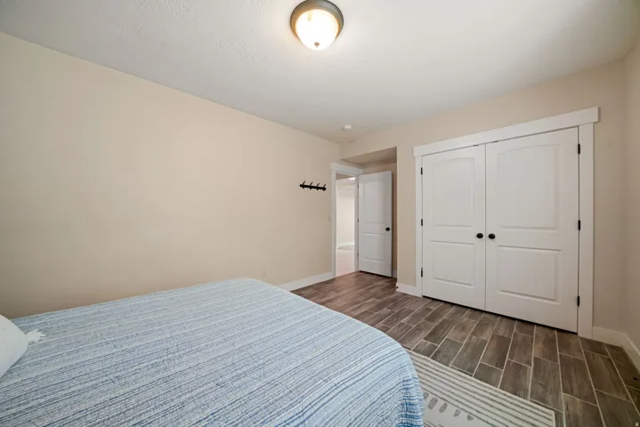 Wood-finish flooring throughout, featuring a double-door closet with arched paneling and dark hardware