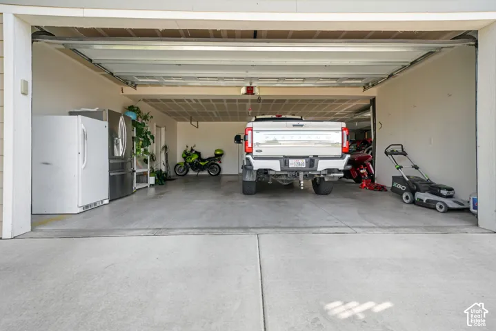 Spacious garage with concrete flooring, overhead garage door, and ample storage capacity