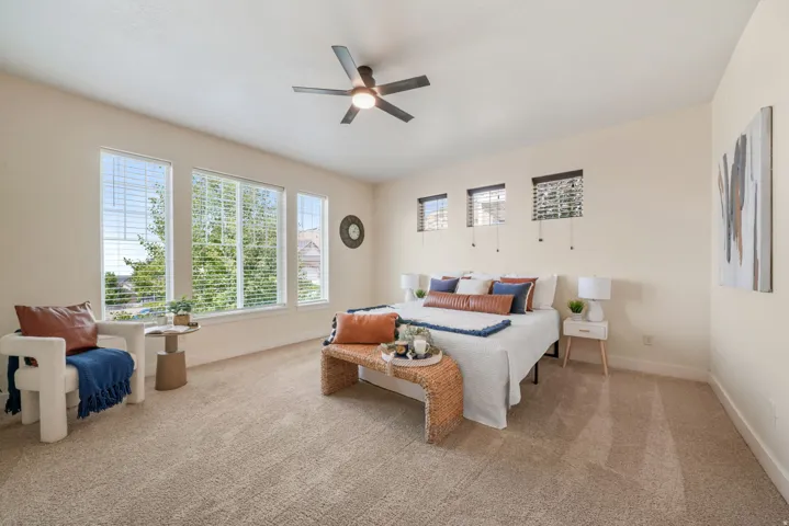 Carpeted room featuring multiple windows with blinds, a ceiling fan with integrated lighting, and neutral wall tones