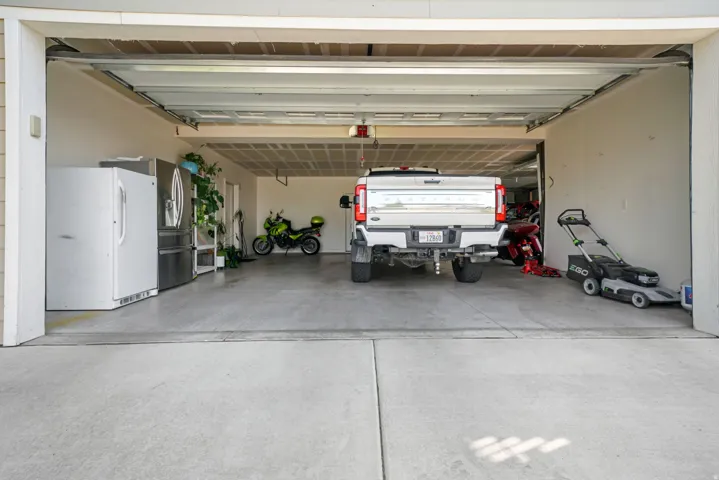 Spacious garage with concrete flooring, overhead garage door, and ample storage capacity