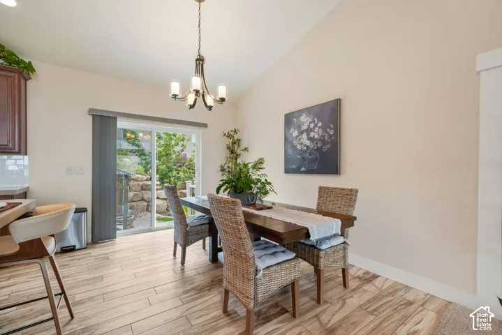 Vaulted ceiling with a chandelier, wood-finish flooring, sliding glass door, and built-in cabinetry