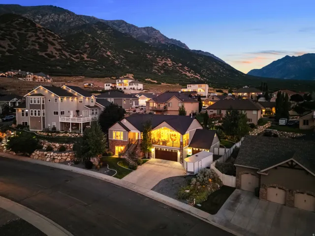 Sloped lot residence featuring a two-car garage, stone and siding exterior, and tiered landscaping