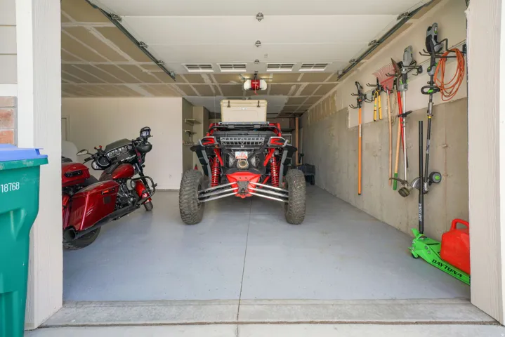 Garage space with a finished concrete floor, exposed ceiling joists, and a wall-mounted storage system